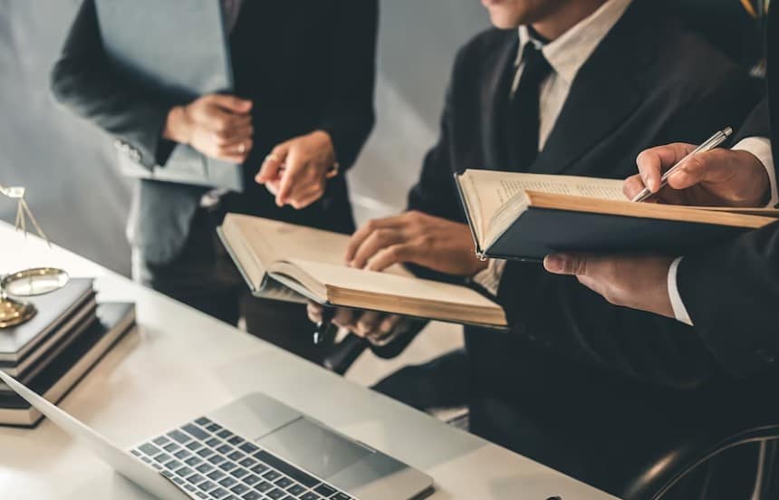 קבוצה של אנשי עסקים שעובדים ליד שולחן עם ספר משפטי לפניהם.